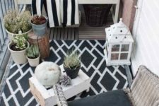 11 a monochromatic balcony with wicker and wooden furniture, black and white textiles, potted plants and candle lanterns