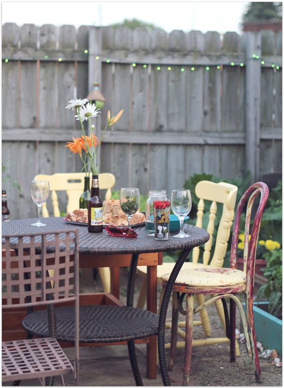 a rounf wicker table and all-mismatching chairs, shabby and rustic ones in different colors