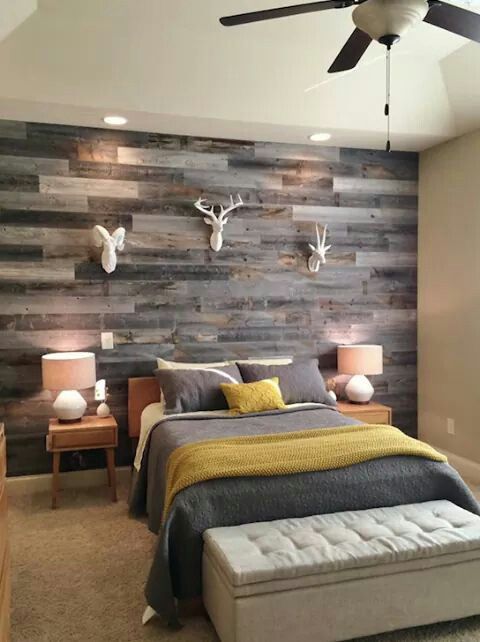 a rustic woodland guest bedroom with a weathered wood plank wall and faux taxidermy for creating an ambience