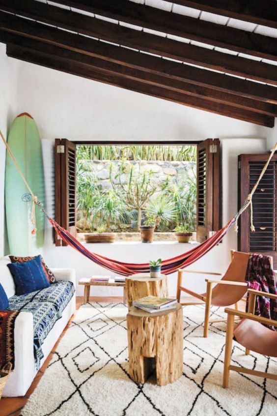 a tropical living room with a colorful striped hammock, a surf and dark stained shutters