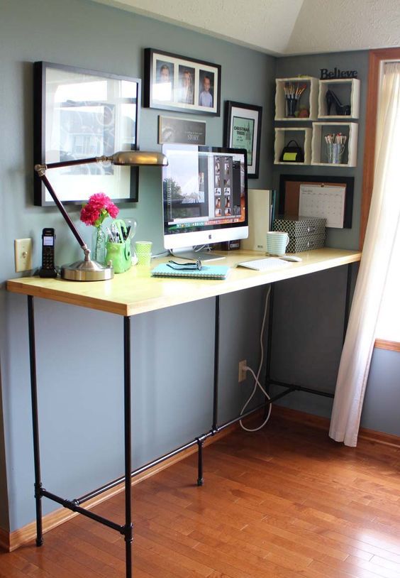 a large yet simple standing desk of blakc piping and a wooden countertop