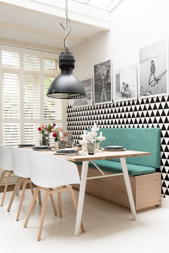 a modern dining space with a green banquette seating and a chevron statement wall