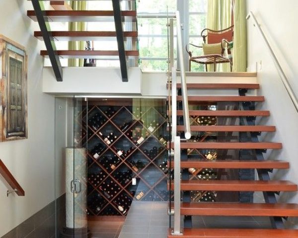 a stylish under the stairs wine cellar with glass doors and wooden shelves on the walls