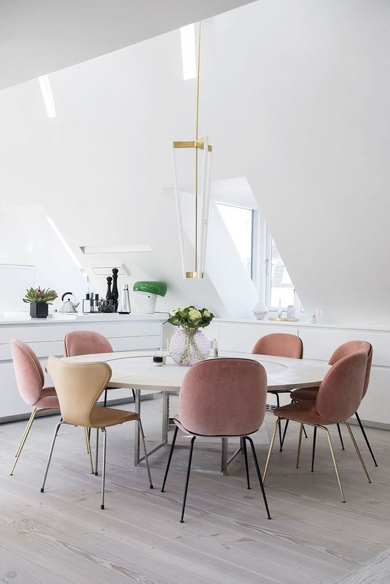 a contemporary dining space with dusty rose chairs for a colorful touch in the neutral space