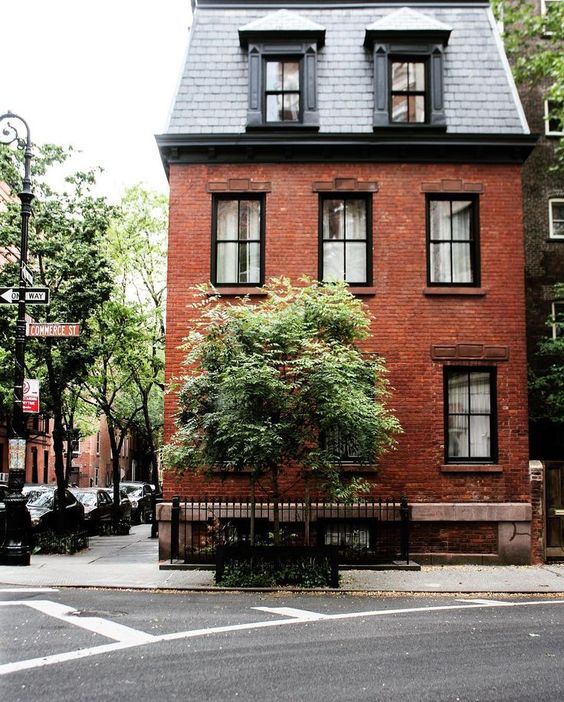 a red brick house with a grey shingle mansard roof looks very chic and eye-catchy