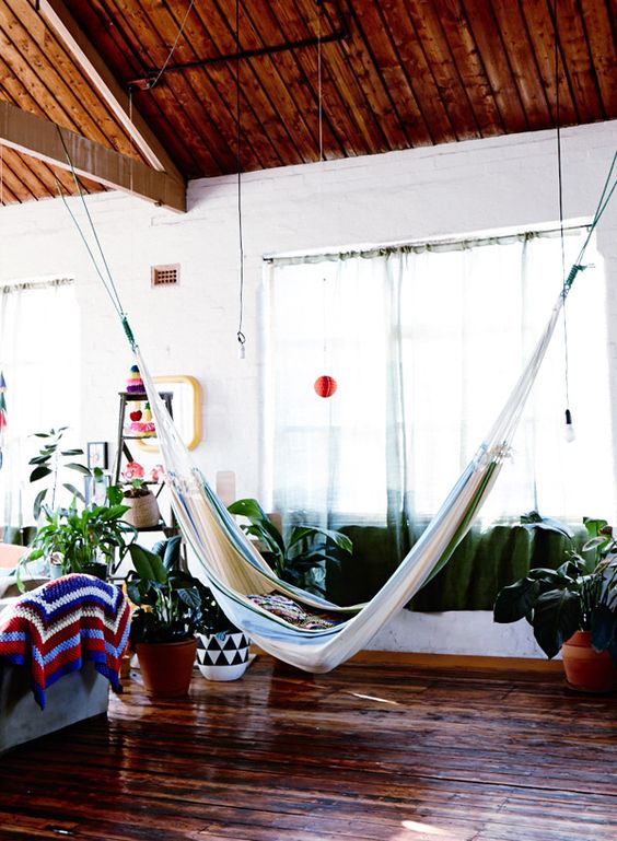 this indoor space feels like outdoors thanks to potted greenery, colorful textiles and a striped hammock
