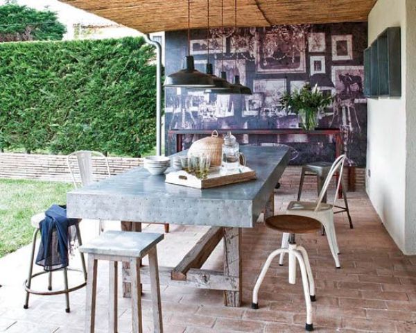 an industrial dining space with a metal covered table and all different chairs from industrial to rustic