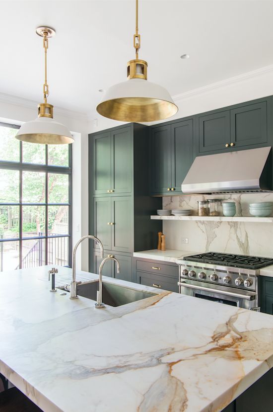 A chic art deco inspired kitchen with black cabinets, touches of gold and marble style granite countertops
