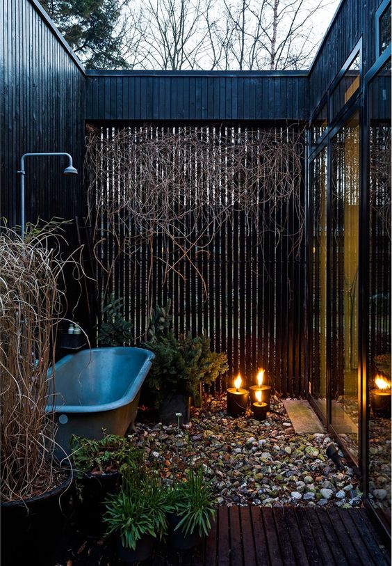 a contemporary space in a small private courtyard, with pebbles on the floor, candles and a grey bathtub