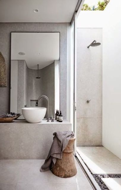 a small outdoor shower done with light-colored concrete and pebbles is built up to the usual indoor bathroom
