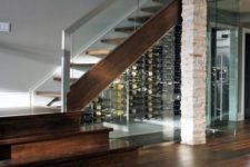 15 a whole wine room under the stairs with glass walls and lights inside looks very inviting