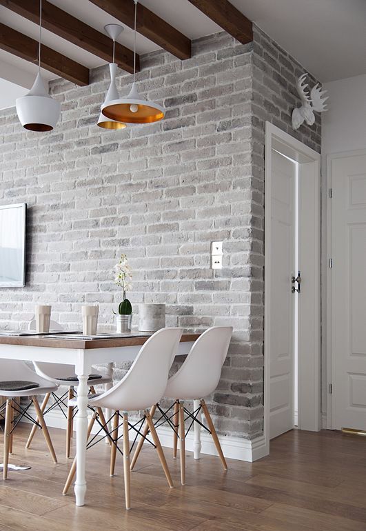 A light colored grey brick wall adds texture to the space and white furniture refreshes the area