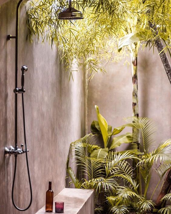 a concrete outdoor shower with hanging and planted greenery for a cool tropical feel