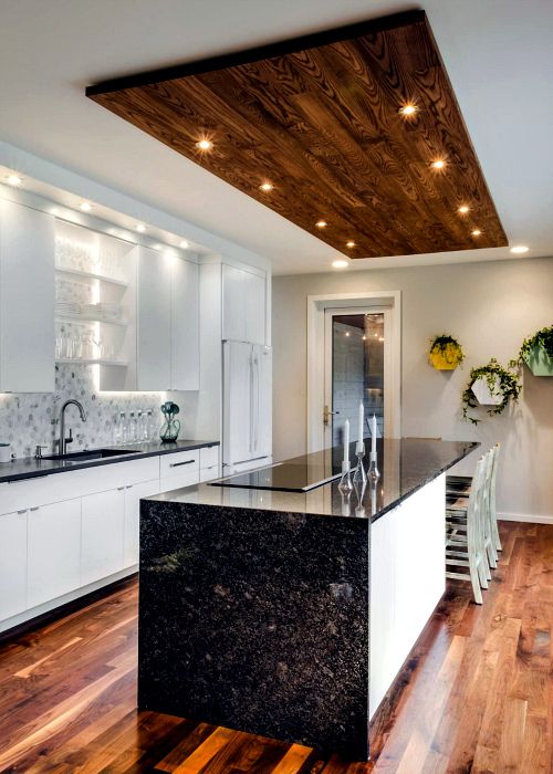a contrasting black and white kitchen with black granite countertops and  touches of wood