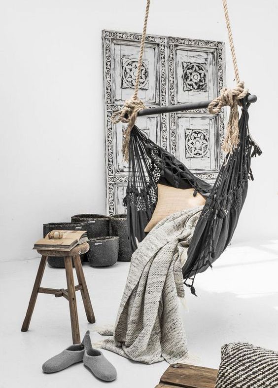 a dark grey hammock chair with pillows and blankets in a natural space with Asian flavors
