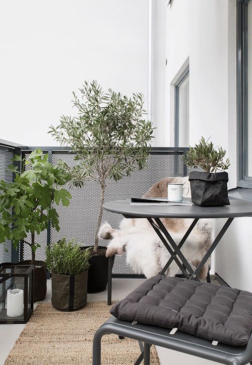 a dark metal folding furniture set, potted greenery and flowers, candle lanterns for a Scandinavian feel
