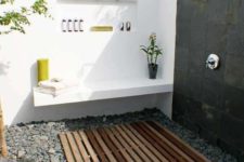 18 a contemporary outdoor shower of white concrete, tiles, pebbles on the floor and a wooden deck