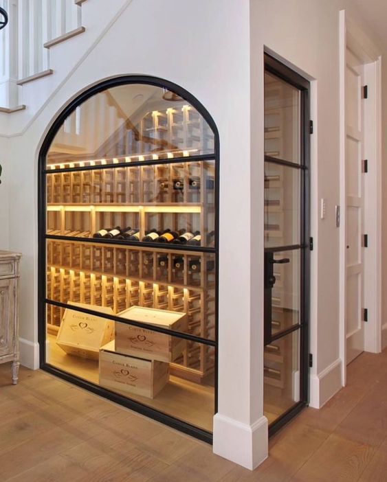 an under stairs wine cellar with an arched glass window and additional lights looks very cool