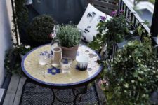 19 a monochromatic balcony with chairs and a lot of potted greenery is spruced up with a colorful mosaiic table