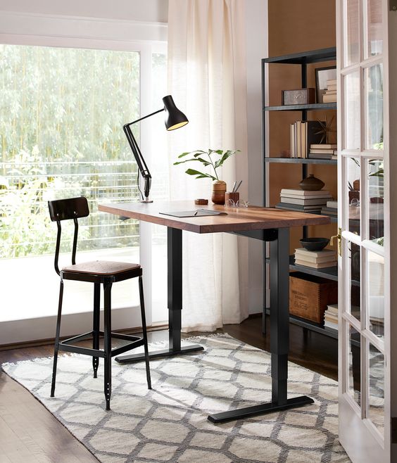 a stylish industrial desk of darkened metal and a wooden countertop plus a matching tall stool
