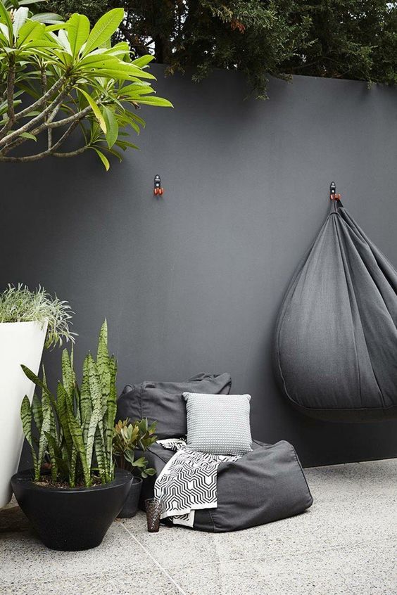 a black bean bag chair and potted plants for a minimalist outdoor space and some printed textiles