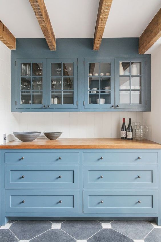 a gorgeous muted blue kitchen with butcher block countertops and matching wooden beams on the ceiling