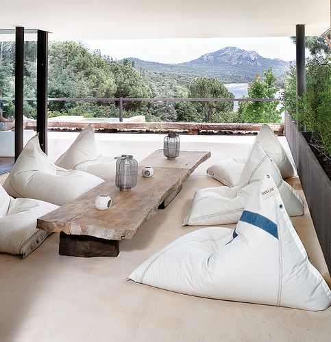 a relaxed casual outdoor dining space with several bean bag chairs and a low raw edge wooden table