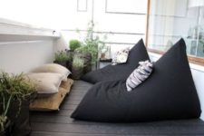 22 a Scandinavian balcony with blackbean bag chairs and neutral pillows plus potted greenery