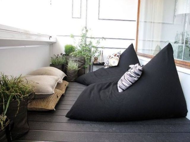 a Scandinavian balcony with blackbean bag chairs and neutral pillows plus potted greenery