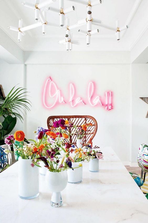 a bright dining space spruced up with tropical touches and a pink neon light word for fun
