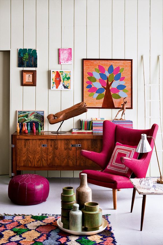 a bright mid-century modern space with a magenta chair and ottoman plus bright artworks