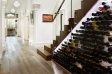 22 a modern wine storage space under the stairs with lots of bottles and additional lights to see them all