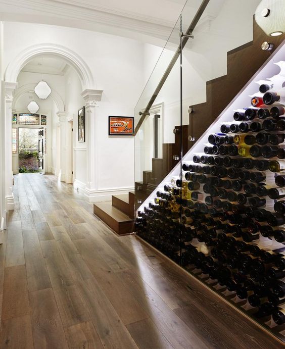 a modern wine storage space under the stairs with lots of bottles and additional lights to see them all