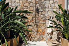 23 a lovely outdoor shower with a stone wall, pebble and stone floor and potted plants