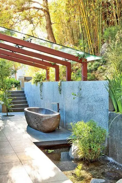 a tranquil outdoor oasis with a stone wall, a little pond and a stone carved bathtub