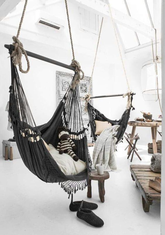 A wabi sabi interior with a couple of dark hammock chairs instead of usual sitting furniture