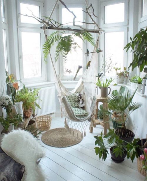 an awkward nook filled with potted greenery and a hammock chair is a great idea to use dead space