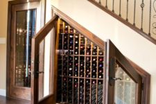 25 an under stairs wine storage space with lots  of shelves for bottles and glass doors
