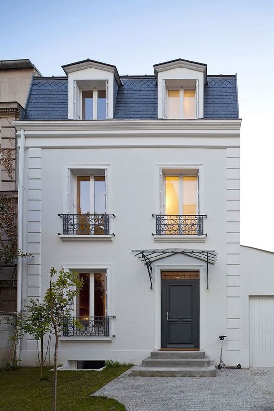 a stylish home in white and grey with a mansard roof used as an additional living space