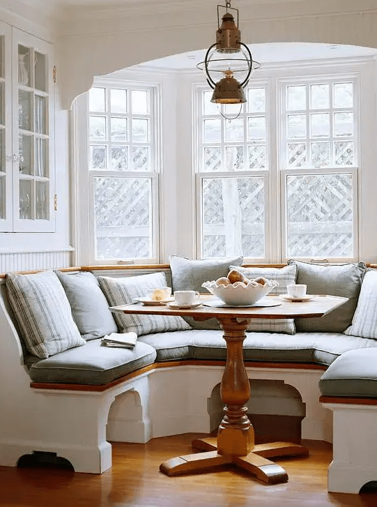 a cozy built-in chalf circle banquette seating with a small rustic table look very inviting