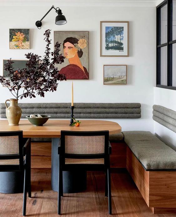 a refined dining room with a banquette seating, a stained table, cane chairs and a gallery wall is a chic space