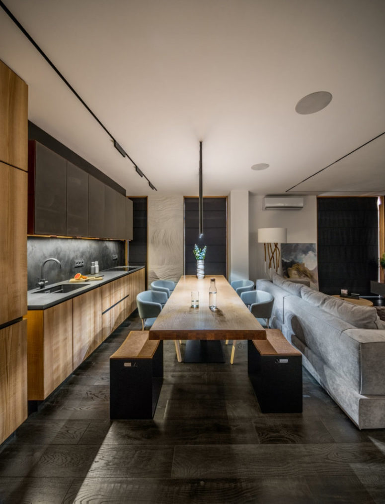 The kitchen and dining space are done in light-colored wood and dark greys for a contrast