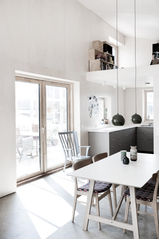 The kitchen and dining spaces are united in the open layout, there are grey cabinets and chairs with colorful cushions
