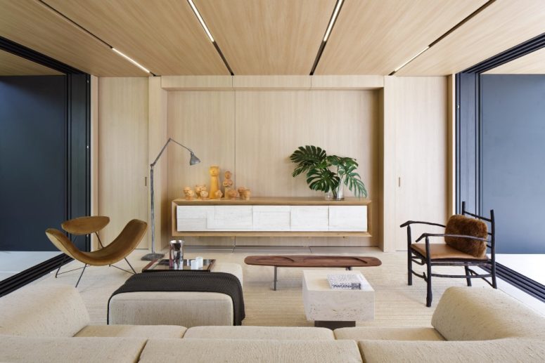 The interiors are done in a neutral color palette, with much wood and plywood, and dark touches add depth to the decor