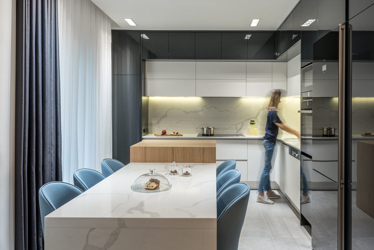 The kitchen is black and white, with a white marble backsplash and lights and a cooking surface of wood