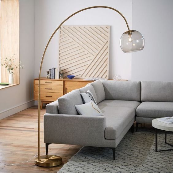a brass curved floor lamp with a smoked glass lampshade will add a refined touch to your space