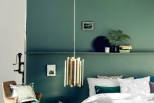 03 a muted green accent wall with a shelf and matching emerald bedding and a pillow