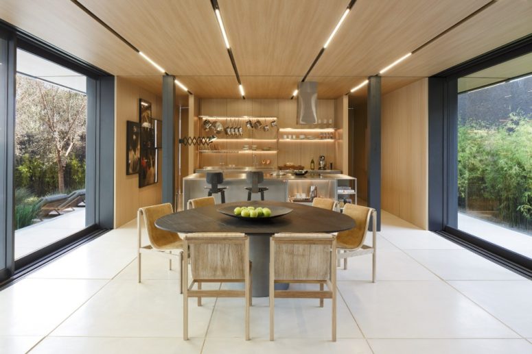 The dining space is united with the kitchen, there's much wood and metal pillars, the space can be opened to outdoors on two sides