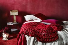 04 an all-red bedroom with a red wall, carpet, pillows and a chunky knit blanket for a passionate look