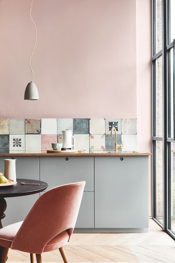 pink walls and matching upholstered chairs spruce up the greys of the kitchen